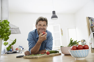 Älterer Mann in seiner Küche isst Tomate - PDF01355
