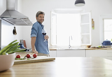 Mature man in his kitchen drinking red wine - PDF01359