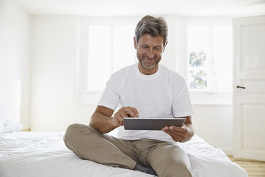 Porträt eines reifen Mannes mit digitalem Tablet im Schlafzimmer - PDF01367