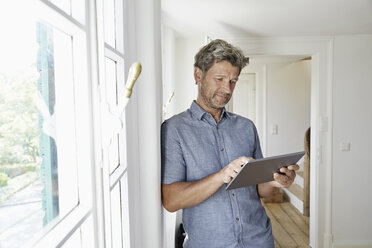 Älterer Mann steht am Fenster und benutzt ein digitales Tablet - PDF01373