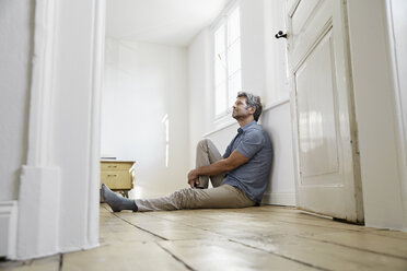 Mature man sitting on floor of his bedroom, daydreaming - PDF01375