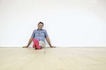 Mature man sitting on ground in empty room - PDF01383