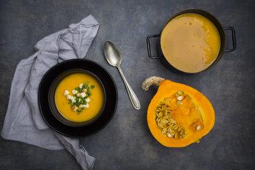 Soup dish of creamed pumpkin soup with croutons and parsley, half of pumpkin and pumpkin soup in pot - LVF06287