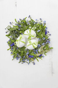 Weiße Eier mit grünen Schleifen in einem Nest aus Vergissmeinnicht, Muscari und Weidenkätzchen auf weißem Hintergrund - GWF05248