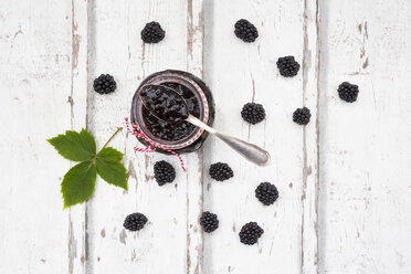 Glass of homemade blackberry jam, blackberries and leaf on wood - LVF06289