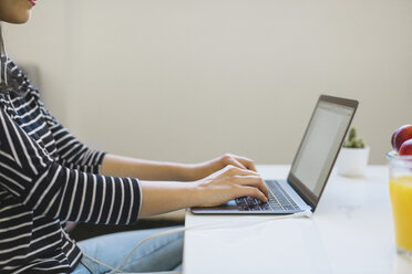Young woman using laptop at home, partial view - MOMF00251