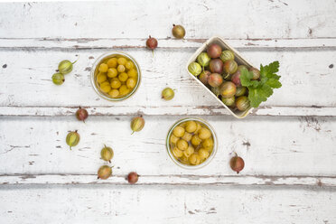 Cardboard box of gooseberries and jars of preserved gooseberries on wood - LVF06292