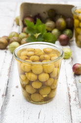 Jar of preserved gooseberries and gooseberries on wood - LVF06294