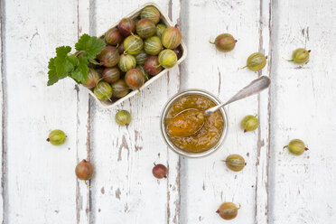 Cardboard box of gooseberries and jar of gooseberry jam on wood - LVF06296