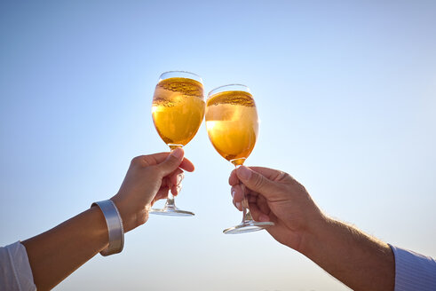 Couple clinking spritz glasses before blue sky - DIKF00279