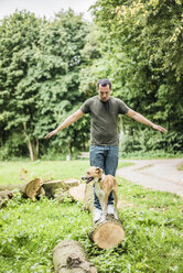 Mann mit Hund balanciert auf einem Baumstamm in einem Park - MOEF00160