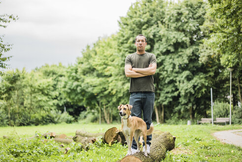 Porträt eines ernsten Mannes mit Hund in einem Park - MOEF00162