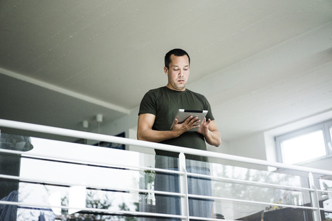 Mann zu Hause mit Tablet im Obergeschoss, lizenzfreies Stockfoto