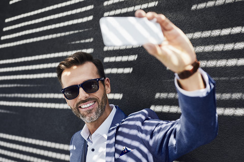 Geschäftsmann macht Selfie mit Smartphone im Freien, lizenzfreies Stockfoto