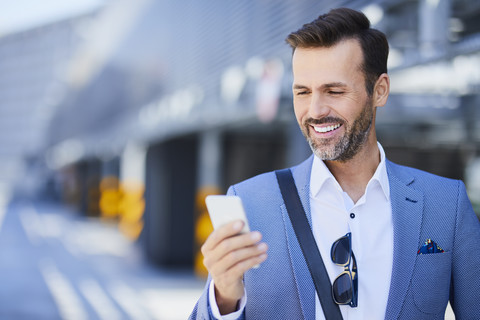 Businessman using phone on parking level outdoors stock photo