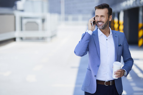 Businessman with coffee talking on phone in the city stock photo