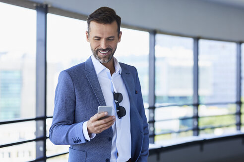 Geschäftsmann mit Telefon und Stadt im Hintergrund - BSZF00039