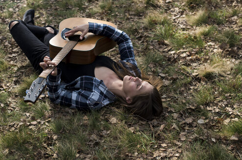 Frau liegt auf einer Wiese und spielt Gitarre - ZOCF00515