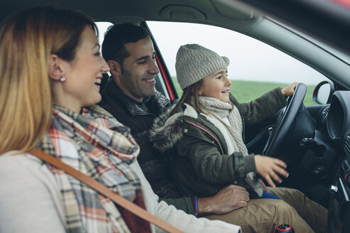 Happy family in car with little girl on father's lap pretending to drive - DAPF00817