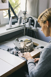 Frau mit Nähmaschine auf einem Tisch im Atelier - JUBF00280