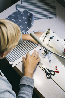 Frau mit Nähmaschine auf einem Tisch im Atelier - JUBF00283