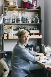 Portrait of confident woman using sewing machine in studio - JUBF00287