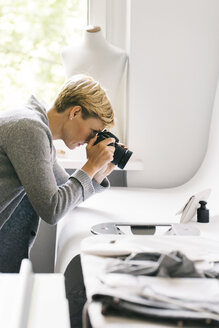 Woman taking picture of clutch bag in studio - JUBF00288