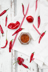 Glas mit Chiliflocken und roten Chilischoten auf einem Küchentuch - LVF06306
