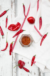 Glass of chili flakes and red chili pods on kitchen towel - LVF06306