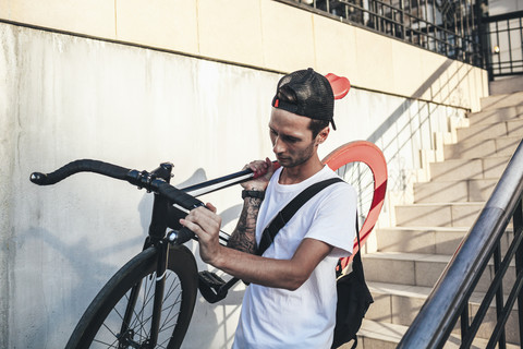 Junger Mann trägt Fixie-Fahrrad die Treppe hinunter, lizenzfreies Stockfoto