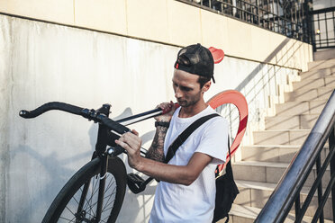 Junger Mann trägt Fixie-Fahrrad die Treppe hinunter - VPIF00182