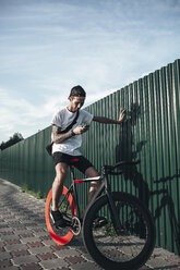 Junger Mann benutzt Handy auf Fixie-Bike - VPIF00186