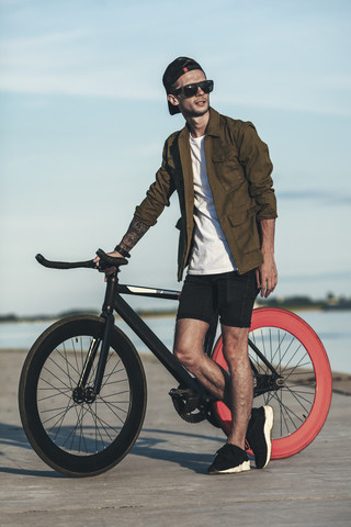 Junger Mann mit Fixie-Fahrrad an der Waterfront, lizenzfreies Stockfoto