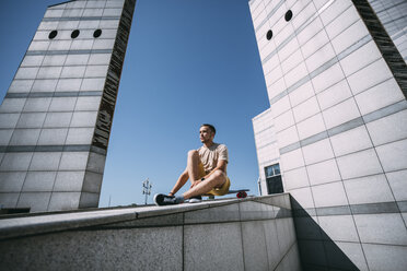 Young man with longboard surrounded by modern architecture - VPIF00206
