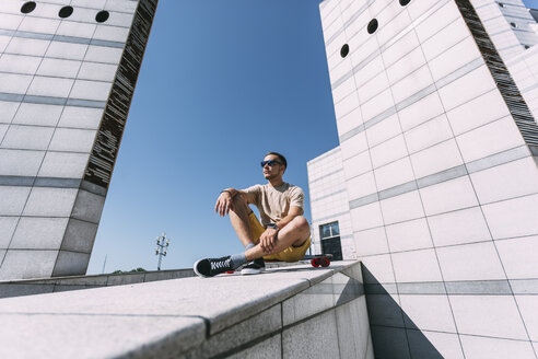 Junger Mann mit Longboard umgeben von moderner Architektur - VPIF00207