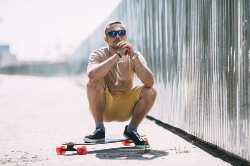 Junger Mann auf Longboard hockend - VPIF00226