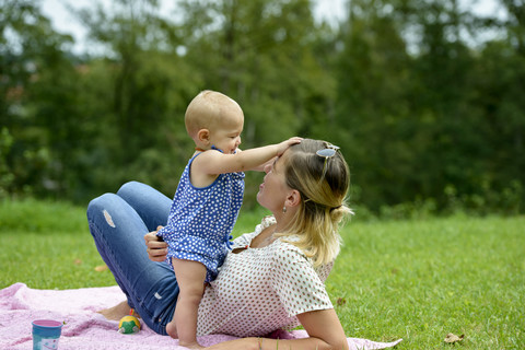 Mutter spielt mit ihrem kleinen Mädchen in einem Park, lizenzfreies Stockfoto