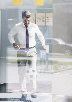 Businessman playing football in office - UUF11849
