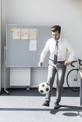 Geschäftsmann spielt Fußball im Büro - UUF11850