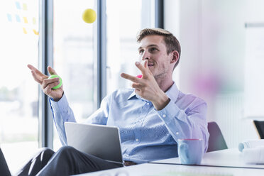 Businessman juggling with balls in office - UUF11860