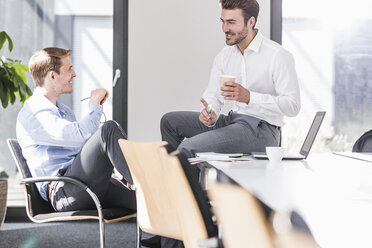 Zwei lächelnde Kollegen arbeiten gemeinsam an einem Projekt im Büro - UUF11862