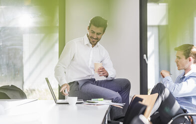 Zwei lächelnde Kollegen arbeiten gemeinsam an einem Projekt im Büro - UUF11863