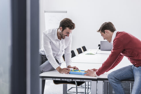 Two colleagues in office playing foosball - UUF11874