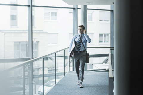 Happy businessman carrying surfboard in office stock photo