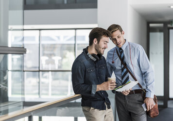 Two colleagues talking on office floor - UUF11886