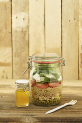 Einmachglas mit gemischtem Salat mit Erbsen, Thunfisch, Couscous, Tomaten, Thunfisch, Feta und einem Glas Vinaigrette-Dressing - ECF01894