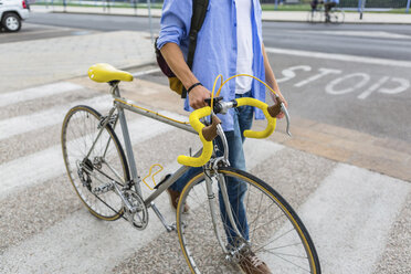 Junger Mann, der sein Fahrrad auf einem Zebrastreifen schiebt, Teilansicht - MGIF00148