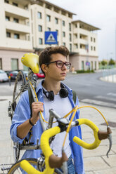 Portrait of young man carrying racing cycle on his shoulder - MGIF00175
