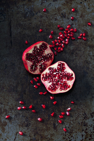 Two halves of pomegranate and pomegranate seed on dark metal stock photo