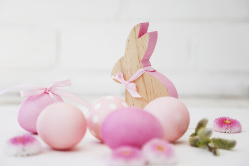 Hand dyed pink Easter eggs with bunny, daisy and catkin decoration on wooden background - GWF05264